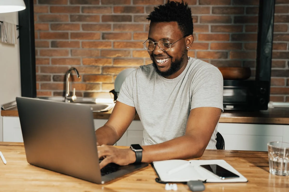Mann arbeitet lächelnd am Laptop in Küche