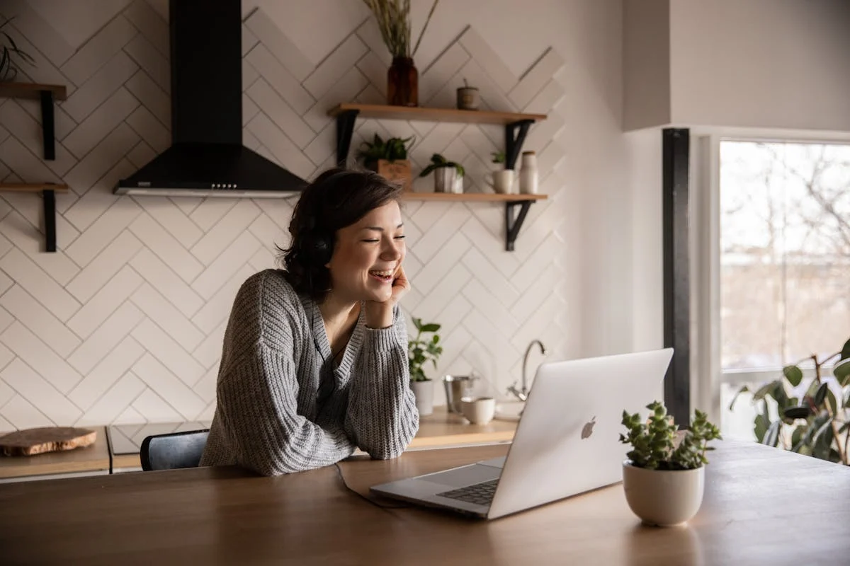 Frau arbeitet lächelnd an einem Laptop zuhause