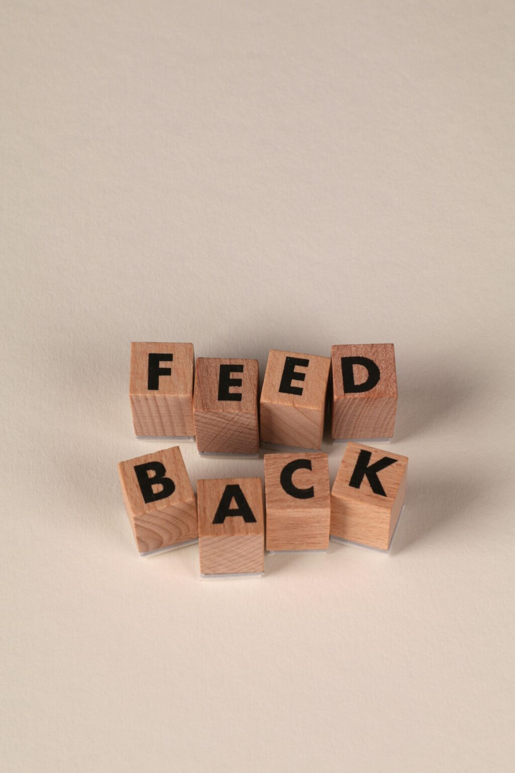 Holzblöcke, die so angeordnet sind, dass sie das Wort FEEDBACK auf einem neutralen Hintergrund buchstabieren.