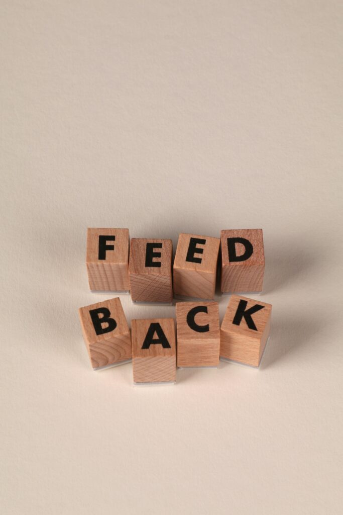 Holzblöcke, die so angeordnet sind, dass sie das Wort FEEDBACK auf einem neutralen Hintergrund buchstabieren.
